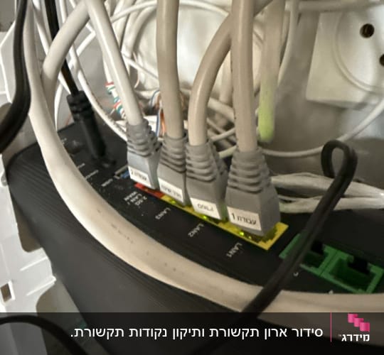 חיבור כבלי רשת מסומנים לנתב בתוך ארון תקשורת ביתי